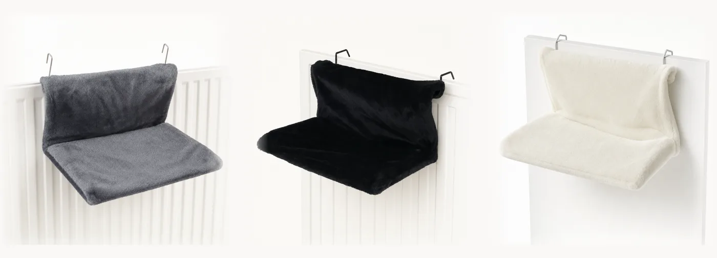 Les trois coloris du hamac de radiateur alignés : peluche grise, noire et crème, crochets métalliques visibles sur les trois